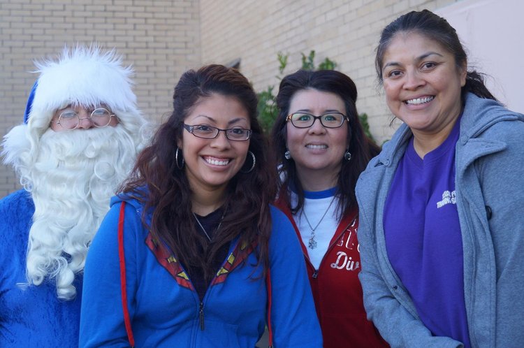 Blue Santa poses with three smiling volunteers