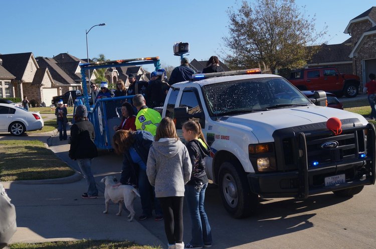 A decorated pickup and Blue Santa trailer stop on a neighborhood street
